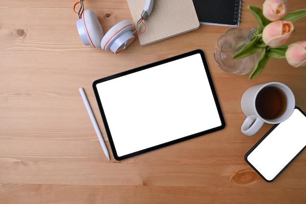 digitales Tablet und Handy mit leerem Bildschirm auf Holzhintergrund.
