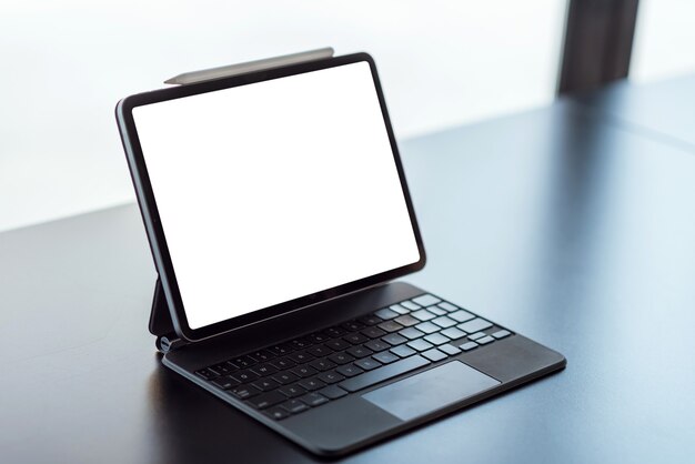 Digitales Tablet und Tastatur mit leerem Bildschirm auf schwarzem Tisch