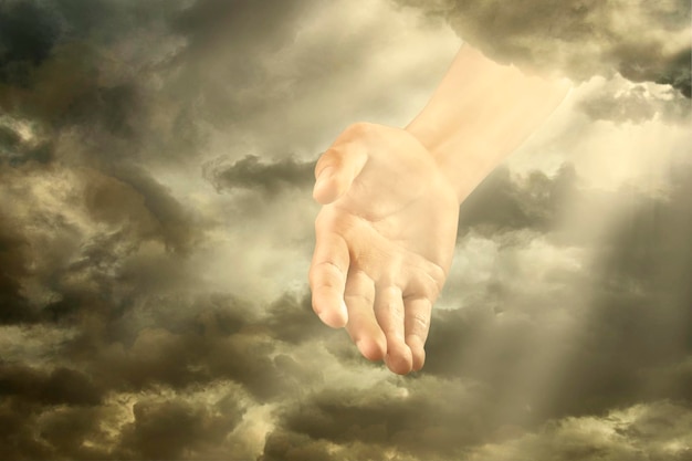 Digitales zusammengesetztes Bild einer Hand inmitten von Wolken am Himmel bei Sonnenuntergang