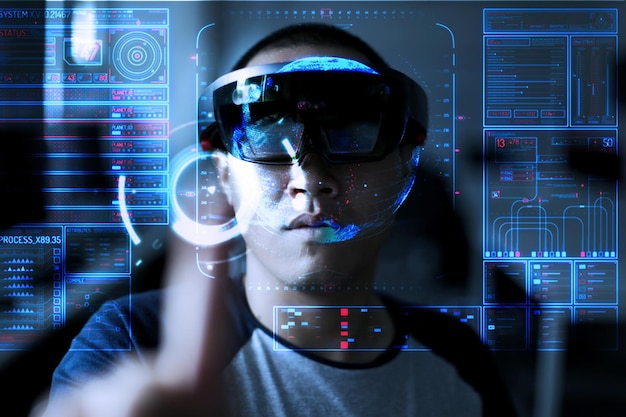 Digitales zusammengesetztes Bild eines jungen Mannes, der einen Virtual-Reality-Simulator trägt, während er mit Daten auf einem unsichtbaren Bildschirm steht