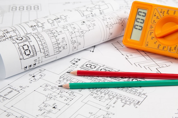 Digitalmultimeter und Bleistifte auf elektrotechnischen Papierzeichnungen