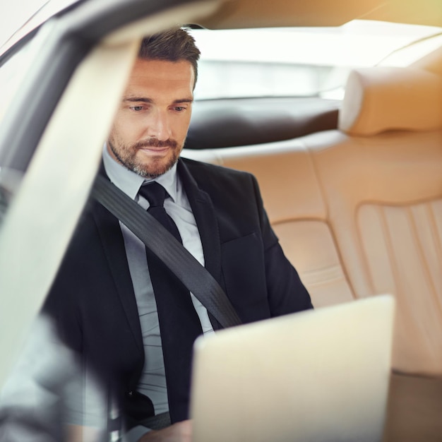 Digitando sua proposta a caminho do trabalho Foto recortada de um empresário no banco de trás de um carro