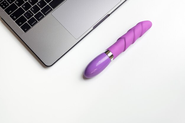 Dildo e laptop na mesa branca com espaço de cópia.