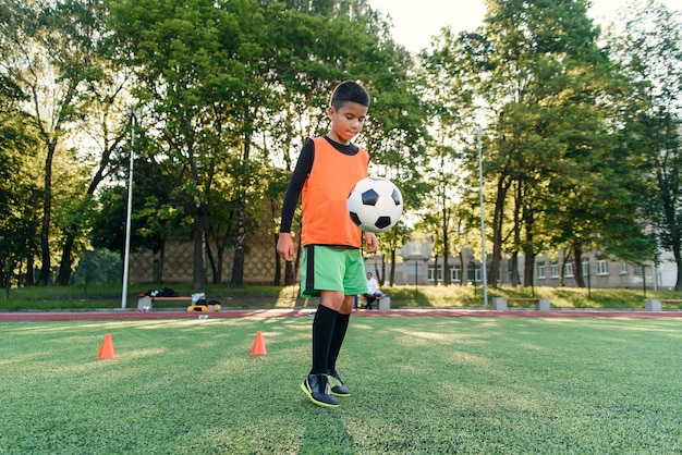 Diligente jugador de fútbol adolescente rellena el balón de fútbol con botas