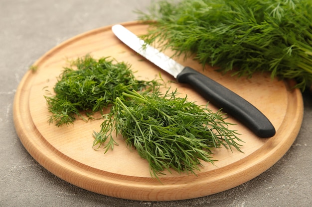 Dill auf Schneidebrett auf grauem Hintergrund schneiden