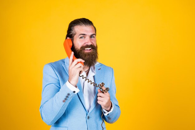 Dilo con teléfonos Hombre barbudo con auricular de teléfono concepto de llamada comercial hombre hablando con un teléfono antiguo hombre barbudo en un traje con teléfono retro mantenerse conectado concepto de servicio al cliente