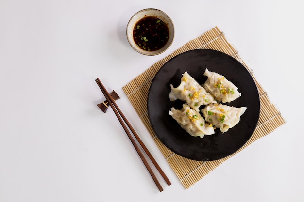 Dim sum chino en un plato negro y palillos