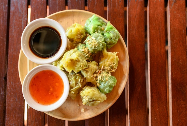 Dim Sum mit gelben und grünen Teigtaschen gefüllt mit Schweinefleisch und Garnelen mit Saucen