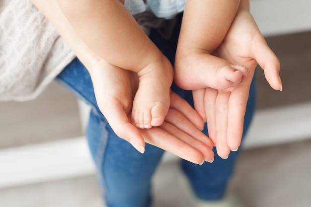 Foto diminutas piernas de bebé recién nacido en manos femeninas