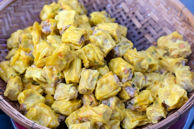 Dimsum al vapor en bambú en el mercado de alimentos de la calle en Tailandia, de cerca. Dim sum un plato chino de pequeñas albóndigas saladas al vapor o fritas que contienen varios rellenos, que se sirve como aperitivo o plato principal.