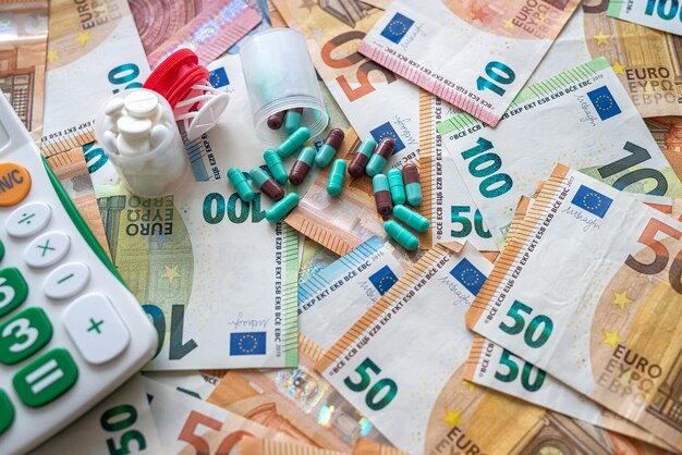 Dinero de billetes en euros con concepto de medicina calculadora y cápsula