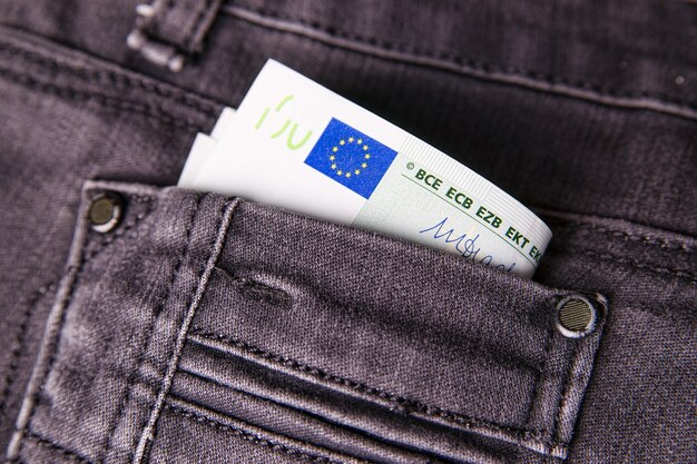 Dinero en el bolsillo de los pantalones vaqueros concepto de finanzas de billetes en euros
