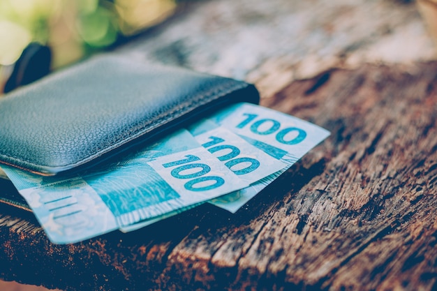 Foto dinero de brasil notas reales, moneda brasileña dentro de una billetera negra. concepto de finanzas, economía y riqueza.