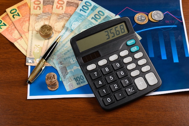 Foto dinero brasileño y una calculadora en un gráfico análisis financiero fondo de madera