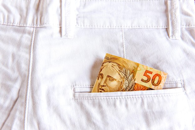 Dinero brasileño Real en el bolsillo de los jeans