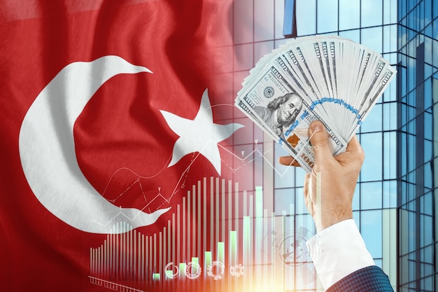 Dinero en la mano de un hombre con el telón de fondo de la bandera de Turquía