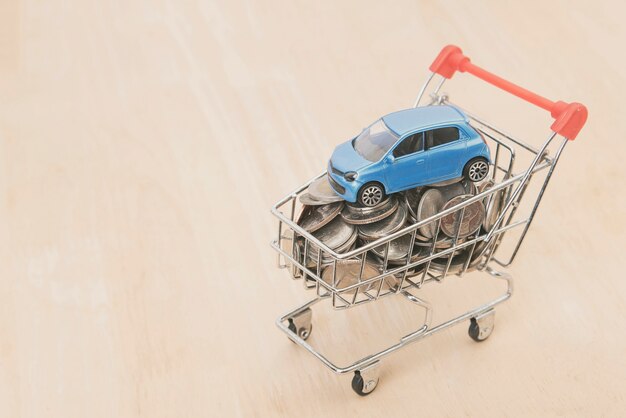 dinero moneda y coche en carrito de compras en la mesa de madera. concepto de préstamo automotriz.