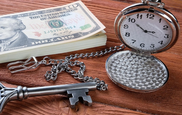 Dinero y reloj en una mesa de madera