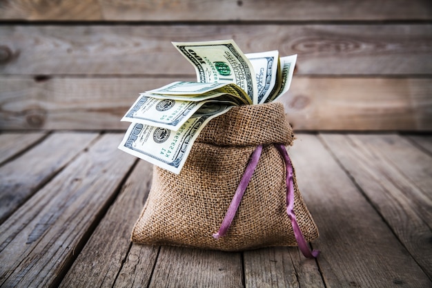 Foto dinero en saco de arpillera en pared de madera