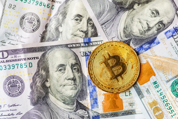 Dinero virtual bitcoin dorado sobre fondo de billetes de cien dólares Intercambio de efectivo de bitcoin por un dólar