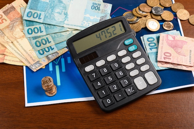 Dinheiro brasileiro e uma calculadora em um gráfico análise financeira fundo de madeira