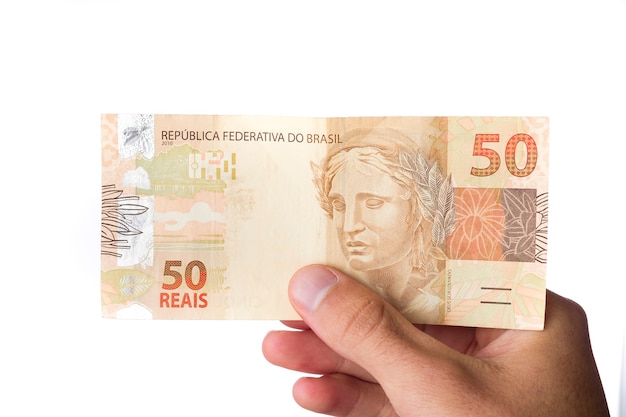 Foto dinheiro brasileiro, homem segurando notas de 50 reais isoladas no branco.