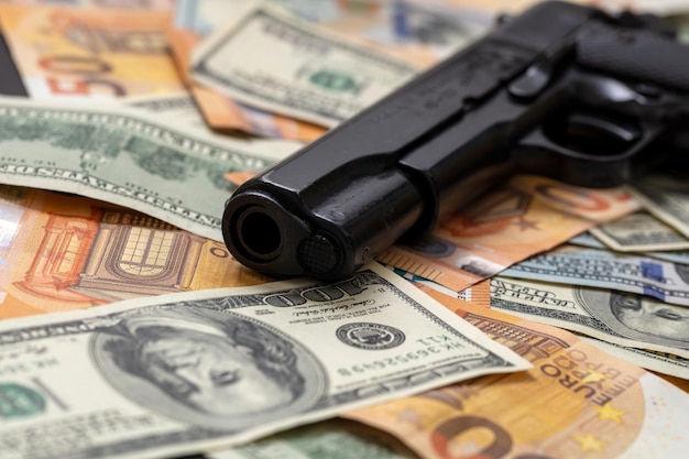 Dinheiro criminoso pistola em fundo de notas de dólar e euro conceito de máfia e corrupção