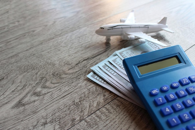 Dinheiro de avião de brinquedo e calculadora na mesa de madeira com espaço para cópia Conceito de viagem e transporte