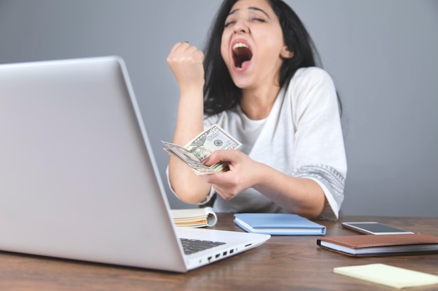 Dinheiro de mão de mulher feliz com computador