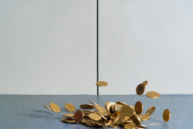 Dinheiro de moedas de ouro caindo na mesa do escritório