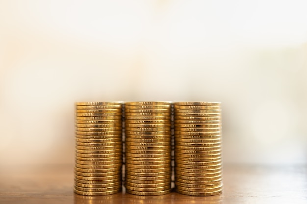 Dinheiro e conceito financeiro. close de três pilhas de moedas de ouro na mesa de madeira com espaço de cópia.