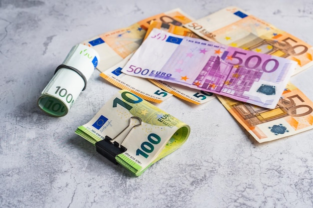 Dinheiro em clipe de papelaria e banda perto da pilha de notas de papel cinco cento e cinquenta euros
