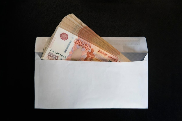 Dinheiro em envelope de papel branco Suborno de rublo em um envelope em fundo preto
