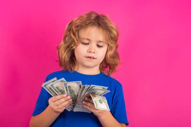 Dinheiro em notas de dólar Garoto mostrando notas de dinheiro em pé sonhando com ricos contra fundo de estúdio isolado