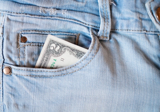 Dinheiro no bolso do jeans Uma nota de dois dólares no bolso de trás do jeans Dinheiro no bolso