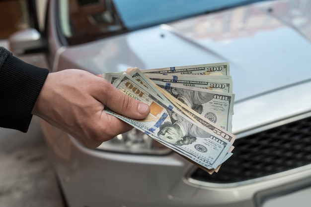 Dinheiro para comprar o carro novo. Conceito financeiro. Dólar na mão