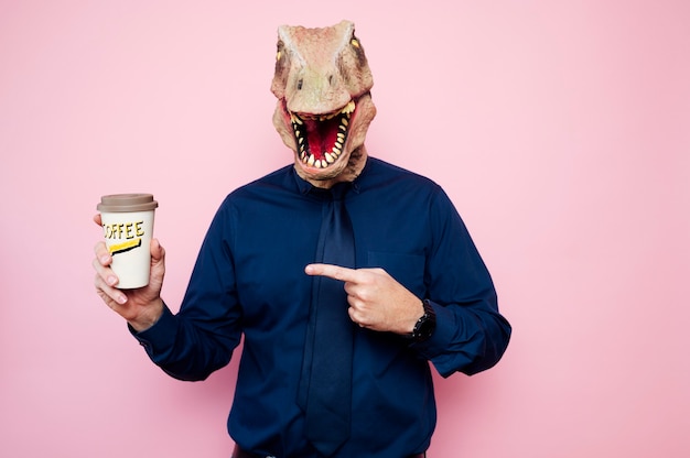 Dinosaurier-köpfiger Mann, der auf recycelbare Pappkaffeetassen zeigt.