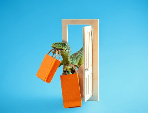 Foto dinossauro verde bonito com sacos de compras em um fundo azul conceito de compras de humor bonito