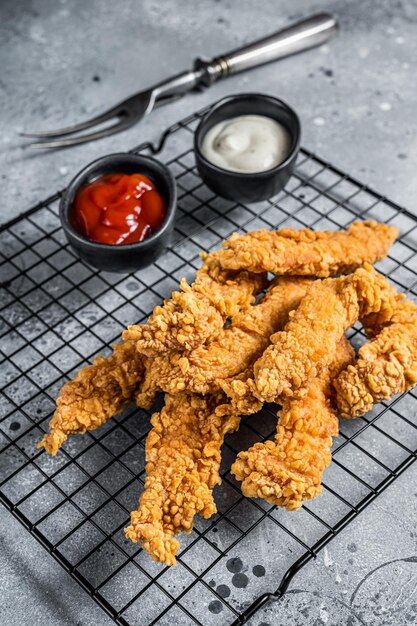 Dip frito filete de pollo Tiras de dedos con salsas Fondo gris Vista superior