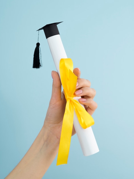 Foto diploma de graduación con cinta amarilla y gorro académico