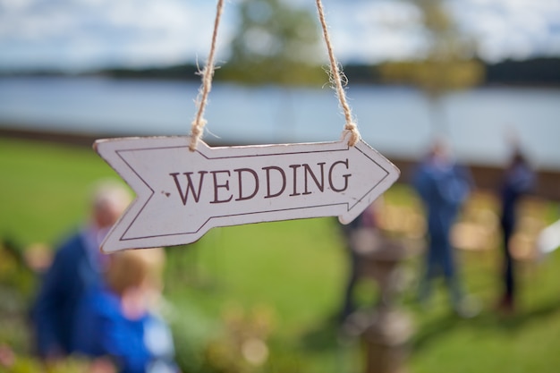 Foto la dirección de madera con el texto de la boda cuelga cerca del lugar de la ceremonia, enfoque selectivo