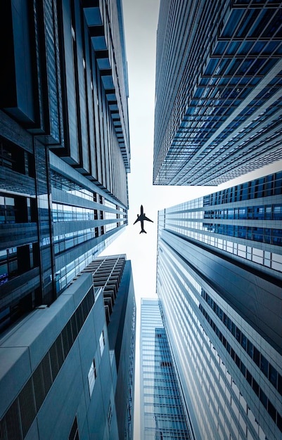 Directamente debajo de la toma de edificios modernos y avión contra el cielo