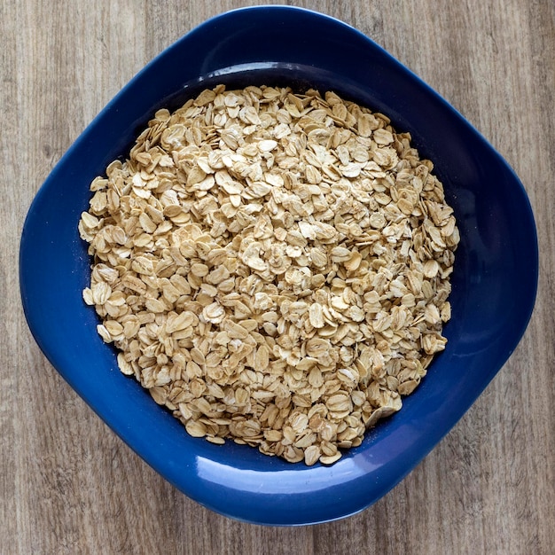 Foto directamente por encima de la toma de copos de avena en un cuenco en una mesa de madera