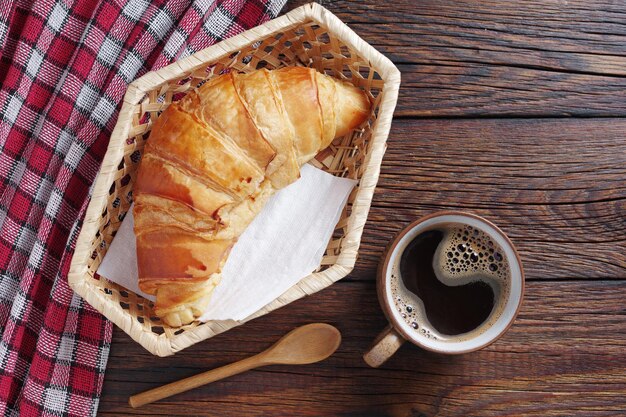 Directamente por encima de la toma de croissant con café para el desayuno en una mesa de madera rústica