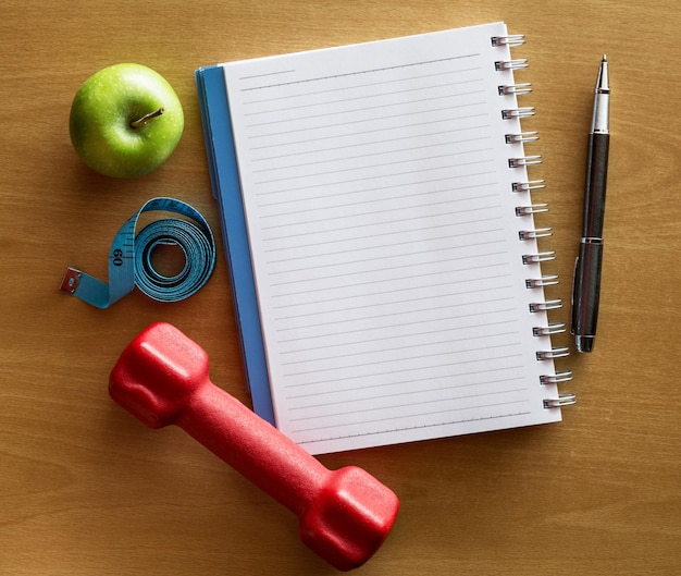 Directamente por encima de la toma del cuaderno en espiral de la abuela Smith manzana y cinta de medición con pesas en la mesa