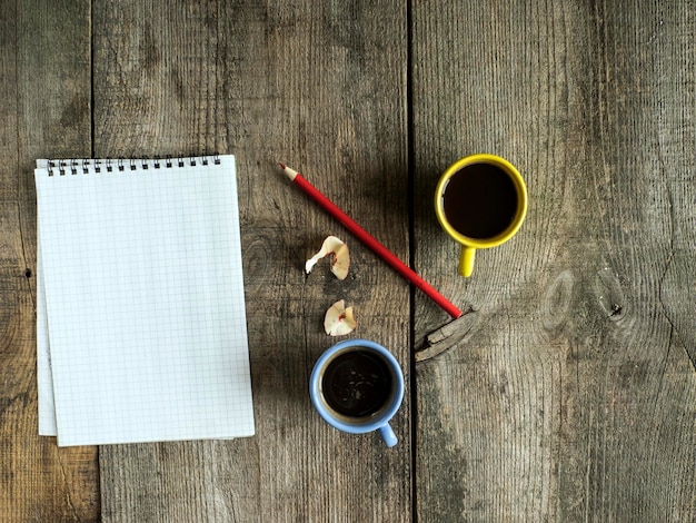 Directamente por encima de la toma de cuaderno en espiral con café y lápiz en la vieja mesa de madera