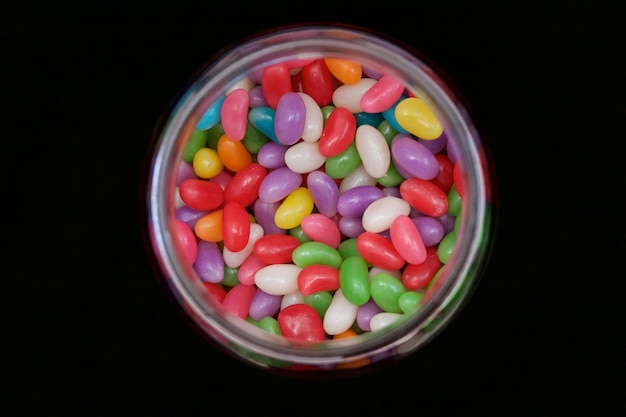 Directamente por encima de la toma de dulces de colores en una jarra sobre un fondo negro