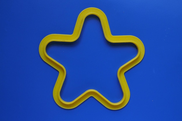Foto directamente por encima de la toma de la forma de estrella juguete de plástico amarillo sobre fondo azul