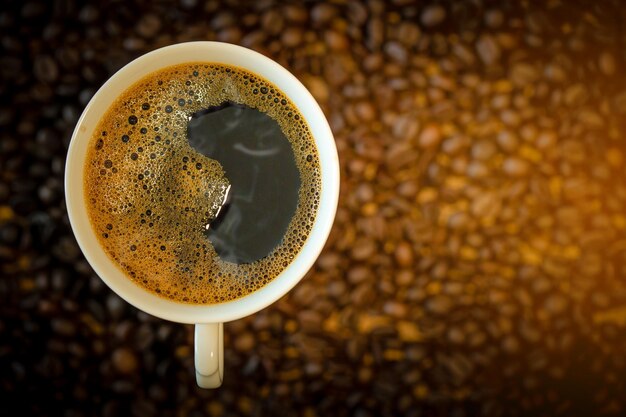 Foto directamente por encima de la toma de granos de café y taza en la mesa