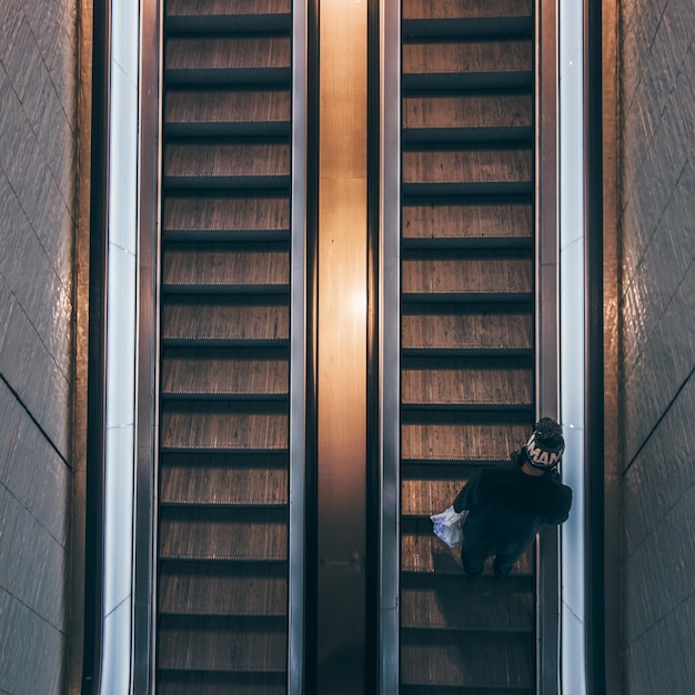 Foto directamente por encima de la toma del hombre en la escalera mecánica en el edificio